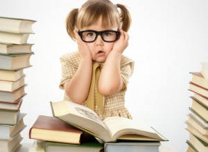Little girl surrounded by books wearing black glasses, back to school concept
