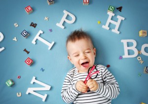 56033302 - one year old child lying with spectacles and letters on blue background